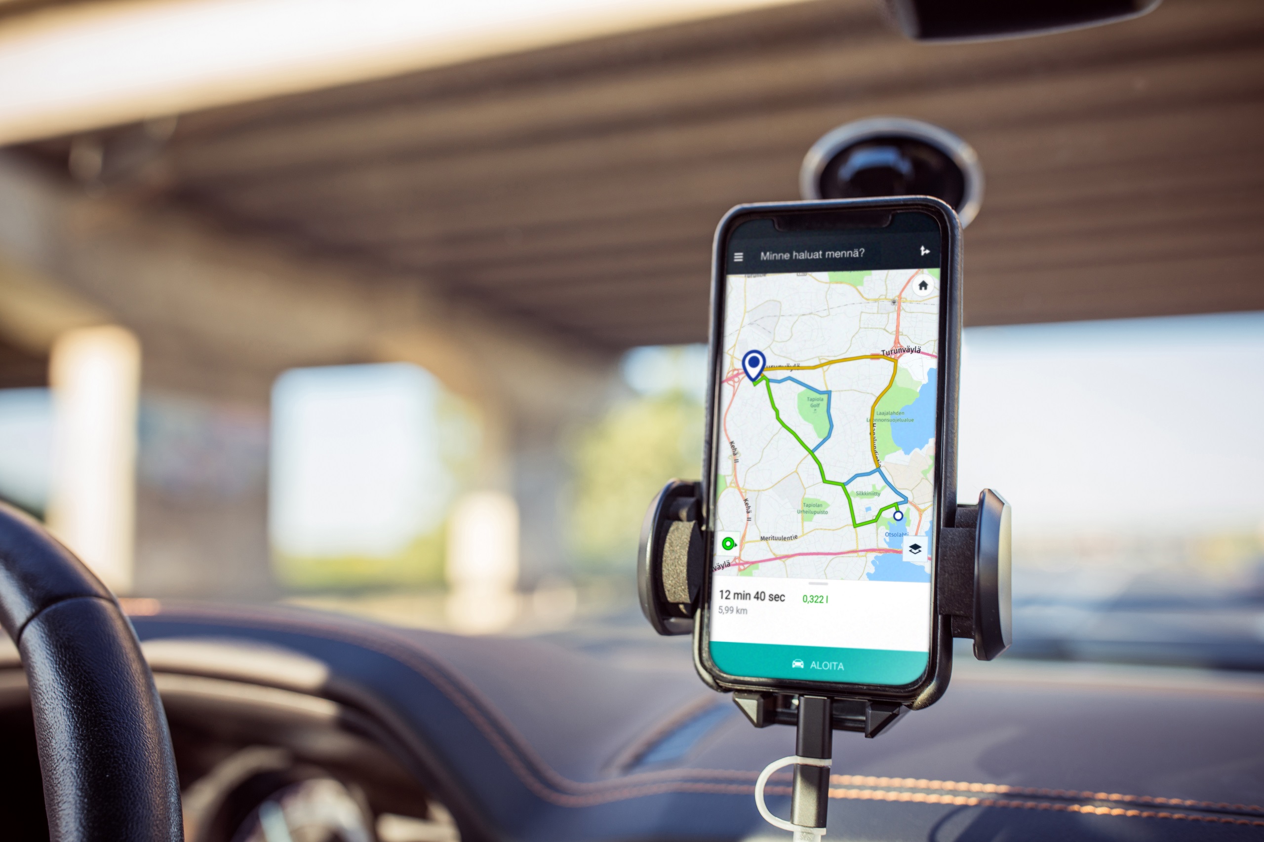The mobile phone is placed in a holder in the car. The mobile phone image shows the driving route, the time it takes to drive to the destination and the route length. 
